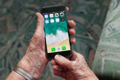 de handen van een ouder persoon met een mobiele telefoon